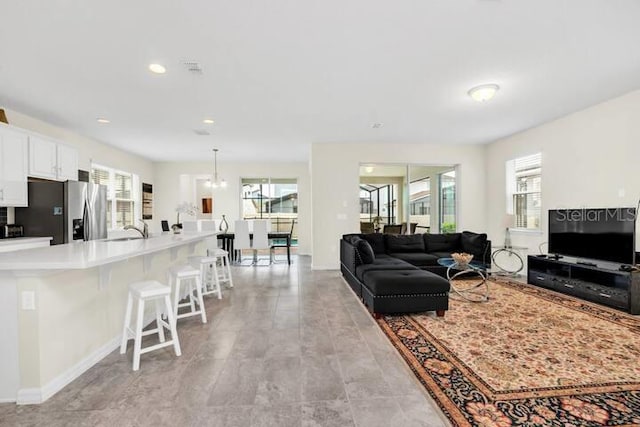 living area featuring recessed lighting, baseboards, and a chandelier