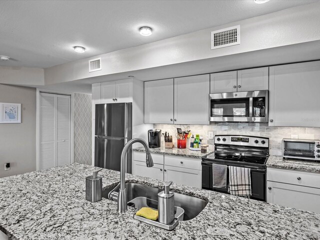 kitchen with a toaster, visible vents, stainless steel appliances, and a sink