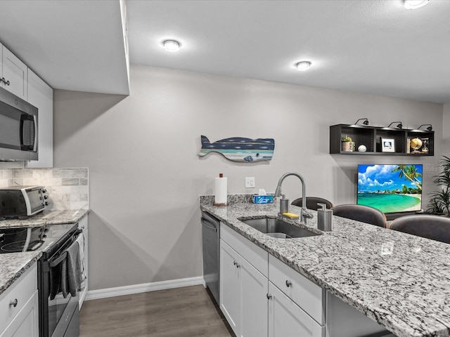 kitchen featuring a sink, tasteful backsplash, wood finished floors, appliances with stainless steel finishes, and a toaster