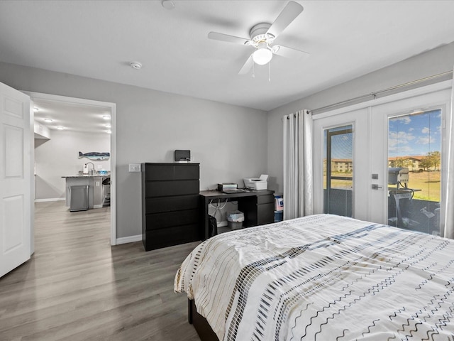 bedroom with access to exterior, baseboards, french doors, wood finished floors, and a sink