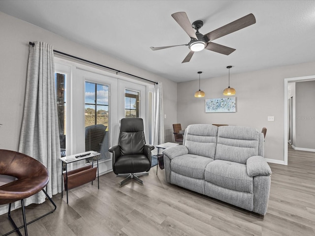 living room featuring french doors, baseboards, light wood-style floors, and a ceiling fan