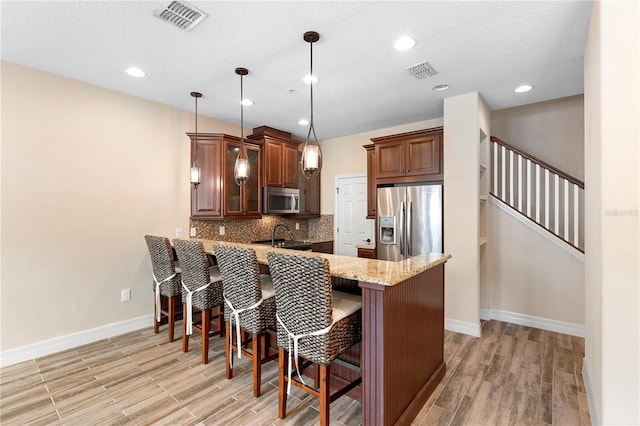 1341 Mill Stream Ln, Winter Springs, FL 32708 - kitchen featuring visible vents, backsplash, appliances with stainless steel finishes, a kitchen breakfast bar, and a peninsula