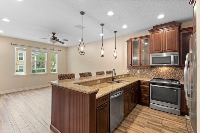 1341 Mill Stream Ln, Winter Springs, FL 32708 - kitchen with a peninsula, a sink, decorative backsplash, stainless steel appliances, and light wood-type flooring