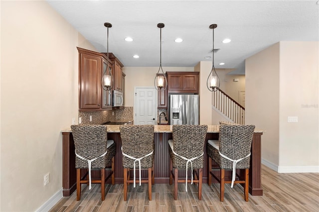 1341 Mill Stream Ln, Winter Springs, FL 32708 - kitchen with backsplash, a peninsula, light wood finished floors, and appliances with stainless steel finishes