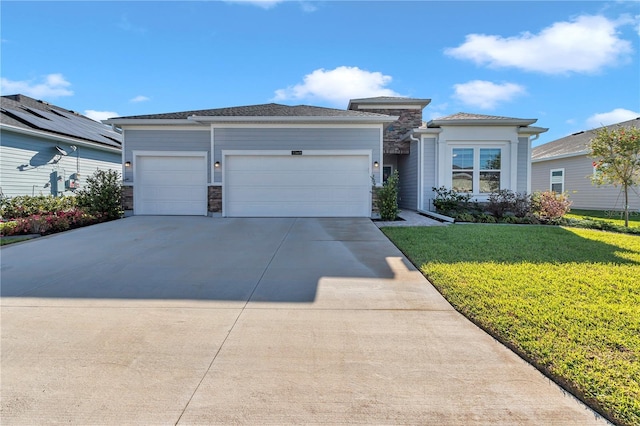 prairie-style home with a front lawn, concrete driveway, a garage, and stone siding