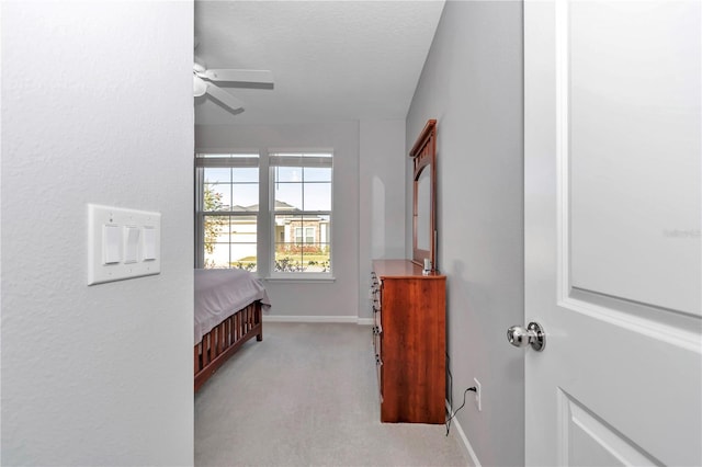 bedroom with baseboards, light colored carpet, and a textured ceiling