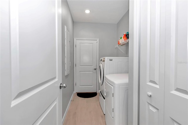 laundry room featuring baseboards, washing machine and dryer, laundry area, and light wood finished floors