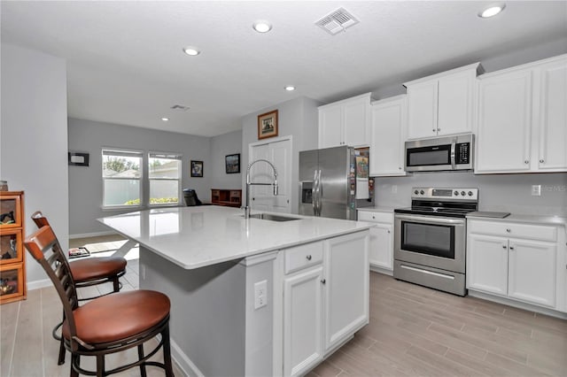 kitchen with visible vents, light countertops, light wood-style flooring, appliances with stainless steel finishes, and a sink