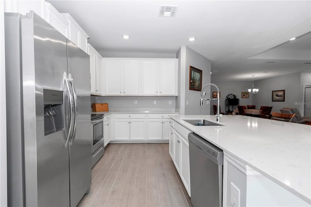 kitchen featuring light stone counters, visible vents, light wood-style flooring, a sink, and stainless steel appliances