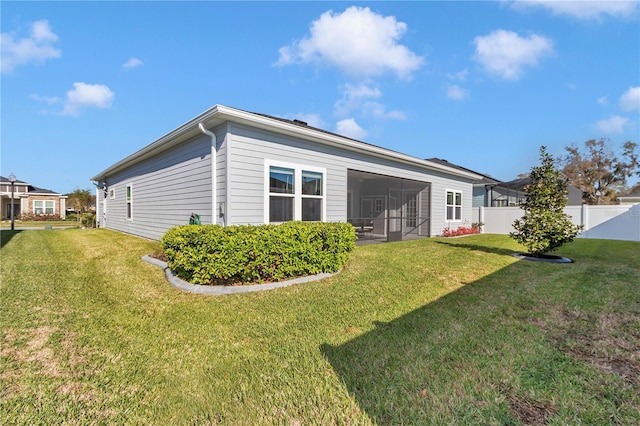 rear view of property featuring a lawn, fence, and a sunroom