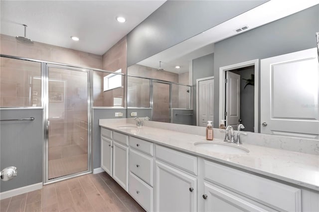 full bath with a sink, visible vents, a stall shower, and double vanity