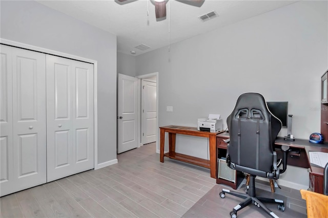 home office featuring visible vents, baseboards, light wood-type flooring, and a ceiling fan