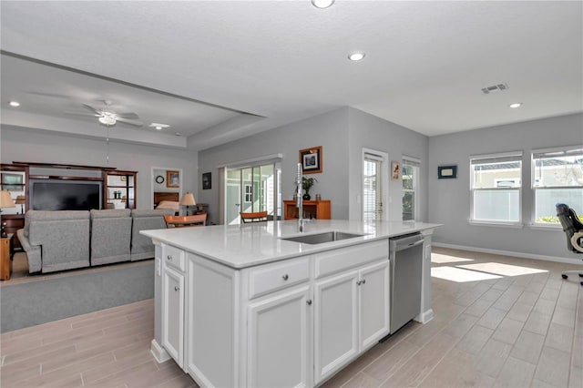 kitchen with visible vents, a sink, open floor plan, stainless steel dishwasher, and a kitchen island with sink