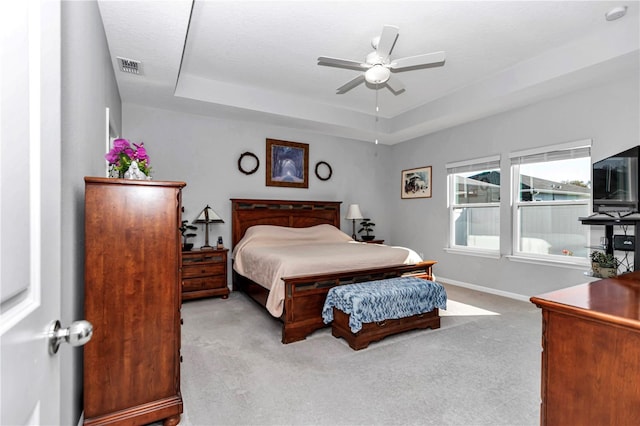 bedroom featuring visible vents, baseboards, carpet floors, a raised ceiling, and ceiling fan