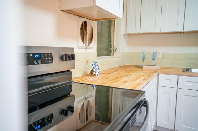 kitchen featuring white cabinetry, tasteful backsplash, and butcher block counters