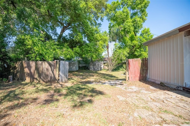 view of yard featuring a storage shed, fence, and an outbuilding