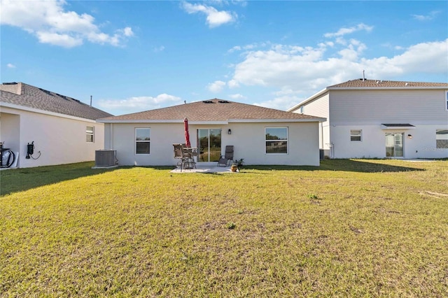 rear view of house with stucco siding, a patio, and a lawn