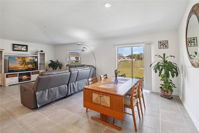 dining area with light tile patterned floors, baseboards, and a lit fireplace