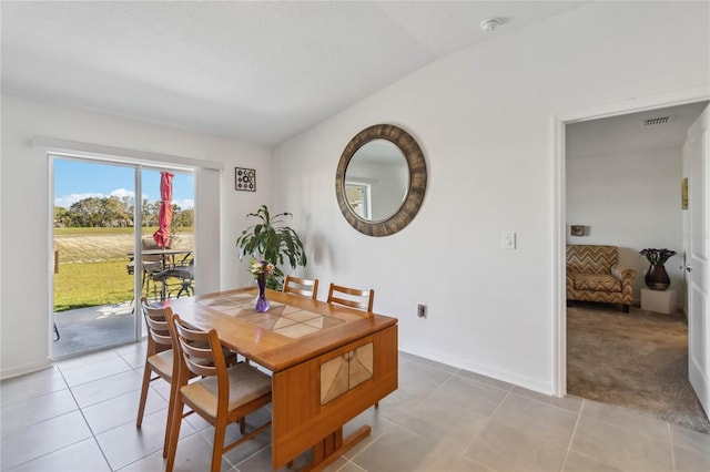 dining area with light tile patterned flooring, light colored carpet, visible vents, and baseboards