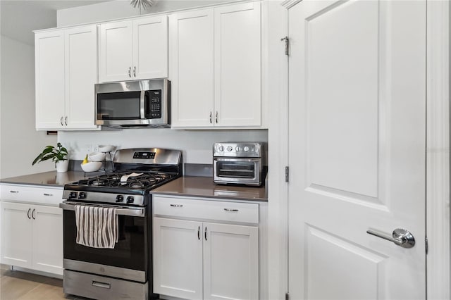 kitchen with dark countertops, white cabinetry, and stainless steel appliances