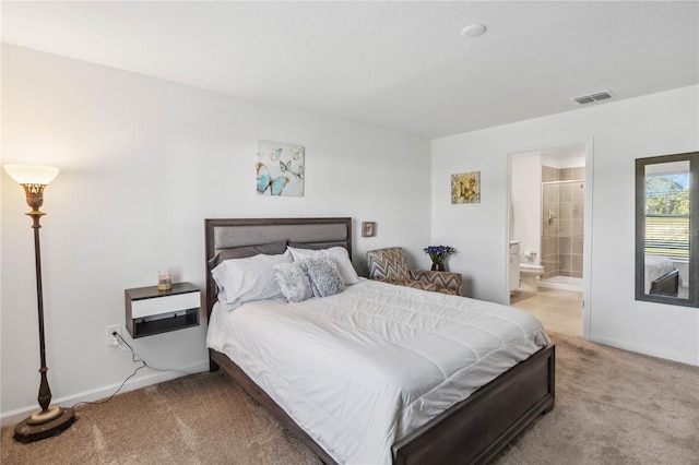 bedroom with visible vents, baseboards, light colored carpet, and ensuite bath