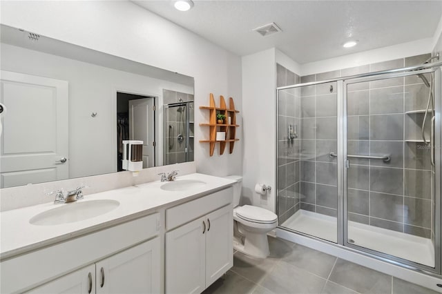 bathroom with a sink, toilet, a stall shower, and tile patterned flooring