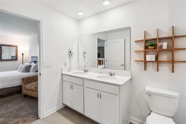 ensuite bathroom with tile patterned flooring, connected bathroom, toilet, and a sink