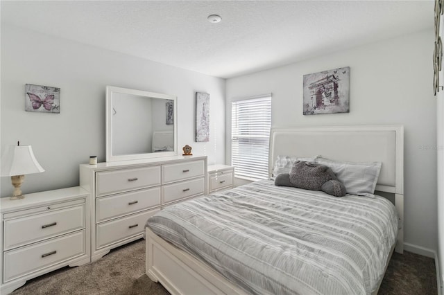 bedroom with a textured ceiling and dark colored carpet