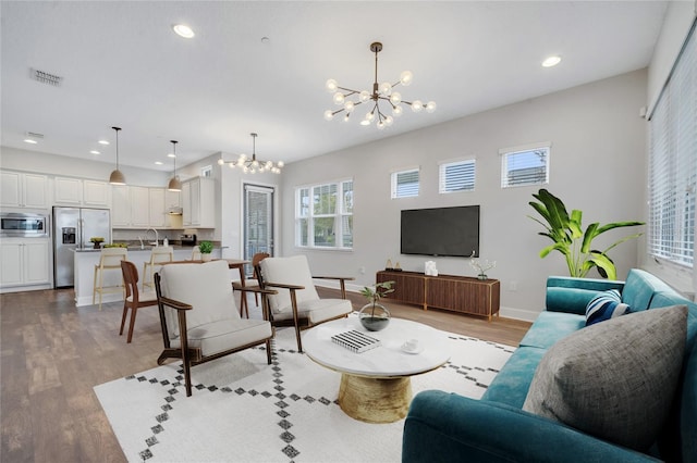 living area with a chandelier, visible vents, recessed lighting, and wood finished floors