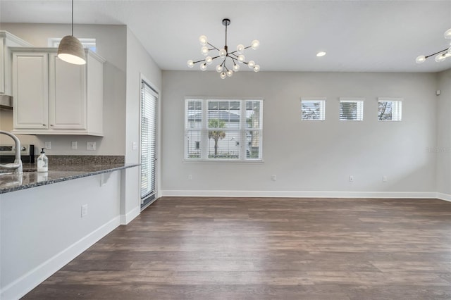 kitchen with dark stone countertops, baseboards, a healthy amount of sunlight, and dark wood finished floors