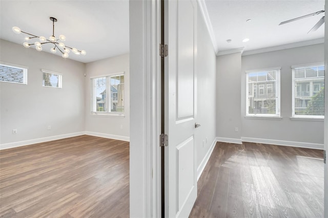 unfurnished room featuring ceiling fan with notable chandelier, wood finished floors, baseboards, and ornamental molding