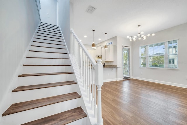 stairs with visible vents, a notable chandelier, wood finished floors, recessed lighting, and baseboards