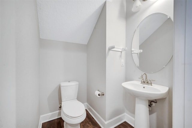 bathroom featuring toilet, a textured ceiling, wood finished floors, baseboards, and vaulted ceiling