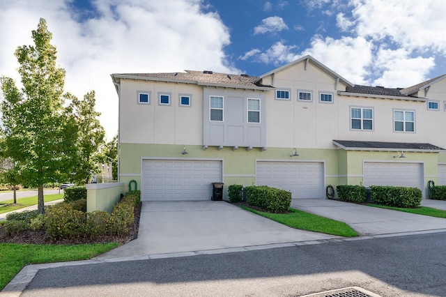 townhome / multi-family property with stucco siding, a garage, and driveway