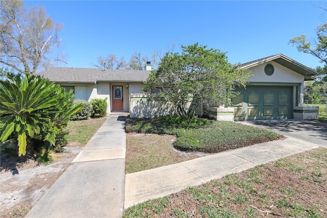 view of front of home featuring concrete driveway, a chimney, a garage, and stucco siding