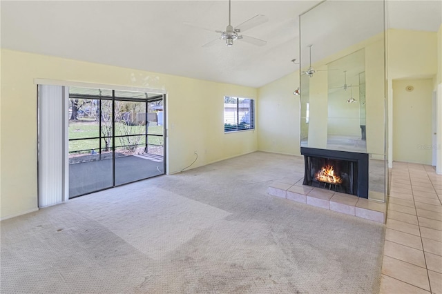 unfurnished living room featuring carpet, ceiling fan, a fireplace, and vaulted ceiling