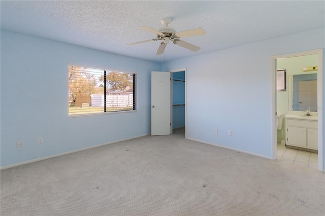 unfurnished bedroom with carpet, baseboards, a closet, a textured ceiling, and connected bathroom