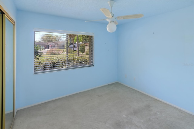 carpeted spare room with a textured ceiling and a ceiling fan