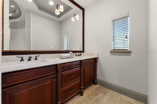 bathroom featuring double vanity, stone tile floors, baseboards, and a sink