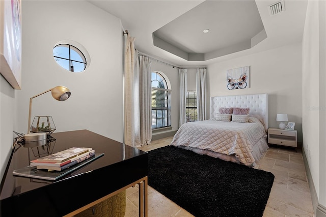 bedroom featuring a tray ceiling, baseboards, visible vents, and stone finish floor