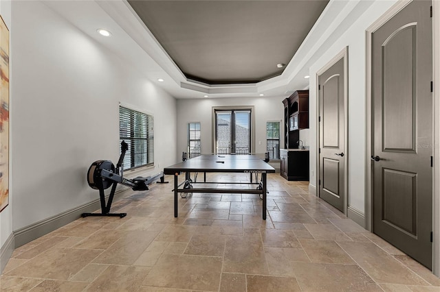 playroom featuring a tray ceiling, recessed lighting, baseboards, and stone tile flooring