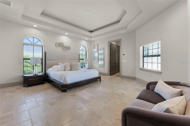 bedroom featuring a tray ceiling, stone tile floors, baseboards, and visible vents