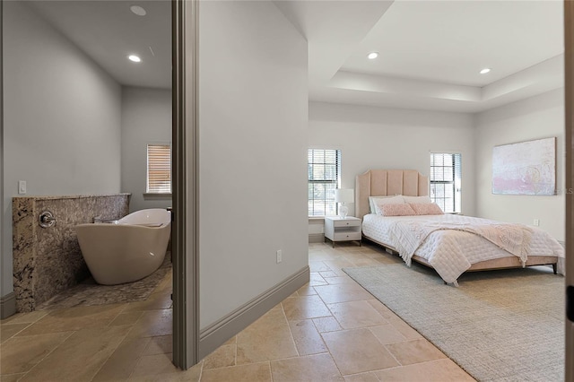 bedroom with a tray ceiling, recessed lighting, baseboards, and stone tile flooring