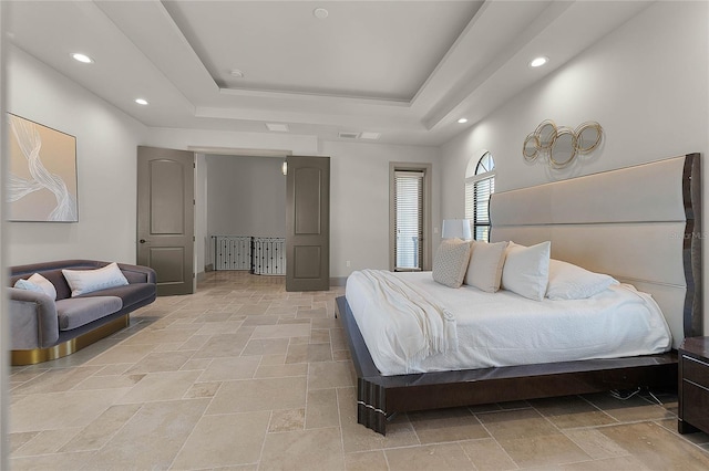 bedroom with recessed lighting, stone finish floor, and a tray ceiling