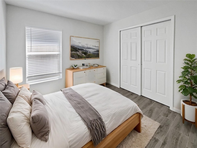 bedroom featuring dark wood-style floors, baseboards, and a closet