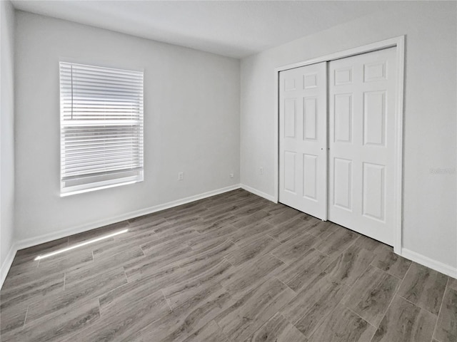 unfurnished bedroom with a closet, baseboards, and wood finished floors