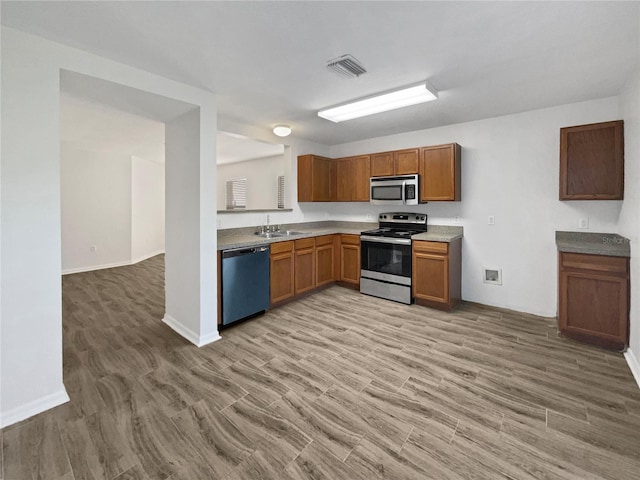 kitchen featuring brown cabinets, light wood-style flooring, visible vents, and stainless steel appliances