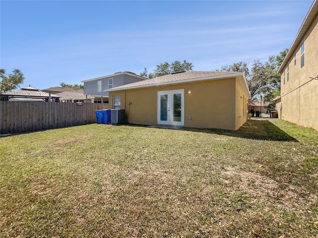 rear view of property with fence, central AC, stucco siding, a lawn, and french doors