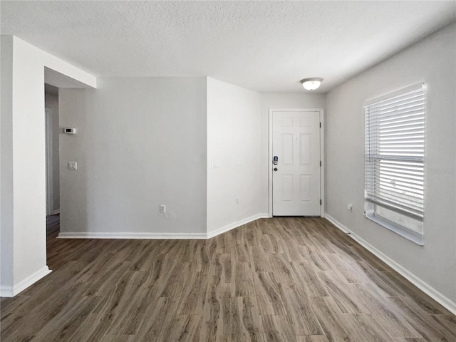 spare room featuring baseboards, a textured ceiling, and wood finished floors