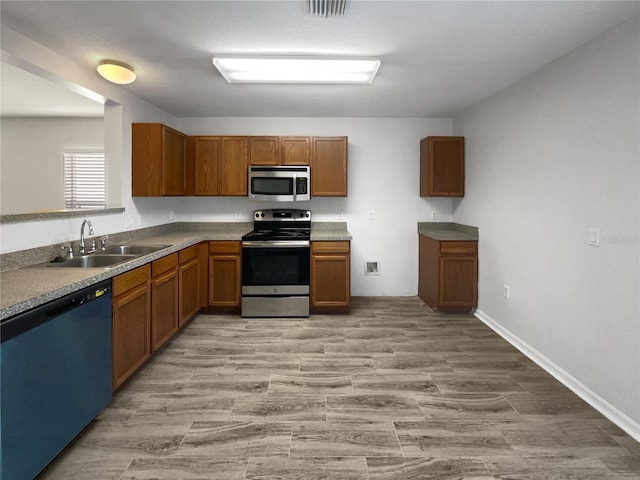 kitchen featuring a sink, brown cabinetry, light wood-type flooring, and stainless steel appliances